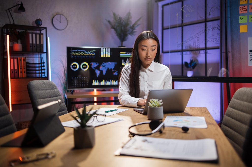 busy Asian woman sitting at office and using laptop