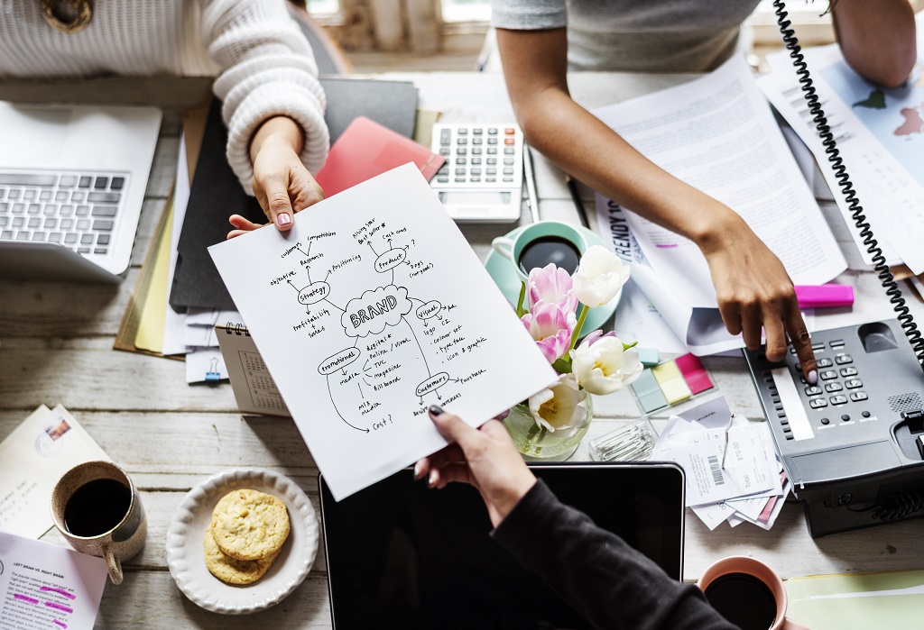 colleagues exchanging a printed branding strategy plan during a collaborative meeting