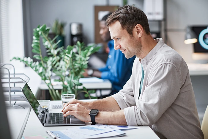 web hosting man working at computer in office side view