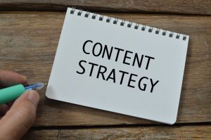 Top view of man hand holding pen writing with text CONTENT STRATEGY. Business concept on how to create SEO content.